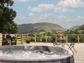 An outdoor area with a hot tub and dining table at Caban Tirion Dinas Mawddwy near Dolgellau