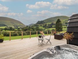 A deck with a hot tub and seating area at Caban Tirion near Dinas Mawddwy