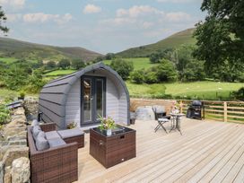 A cabin on a wooden deck with outdoor furniture and grill at Caban Tirion Dinas Mawddwy near Dolgellau