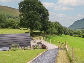 An outdoor area with a deck, chairs and table with trees and mountains at Caban Tirion Dinas Mawddwy near Dolgellau