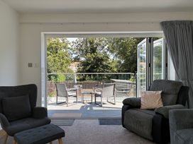 A living room with armchair and sofa leading to a patio at The Swanage Rail Lookout in Swanage