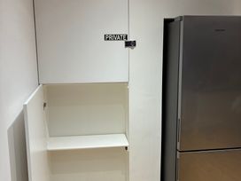 A cabinet and refrigerator in a kitchen at The Swanage Rail Lookout in Swanage