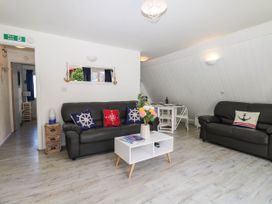 A living room with two black sofas, a white coffee table with flowers, and a small dining table at Chalet 58 - The Beach House in Kingsdown