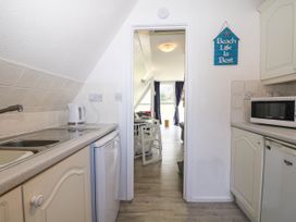 A kitchen with appliances and a sign Beach Life Is Best on the wall at Chalet 58 - The Beach House in Kingsdown