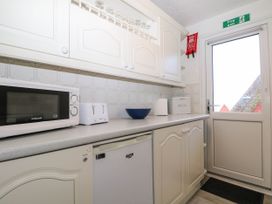 A kitchen counter with a microwave, toaster, bowl, paper towel holder, and bread box near a door at Chalet 58 - The Beach House in Kingsdown
