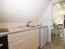 A kitchen with a sink kettle dishwasher and countertop looking into a dining area at Chalet 58 - The Beach House in Kingsdown
