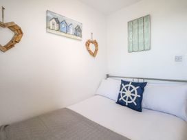A bed with a blue pillow and white bedding in a bedroom with nautical wall decor at Chalet 58 - The Beach House in Kingsdown