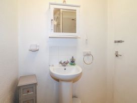 A bathroom with a pedestal sink mirror cabinet soap dispenser and small storage unit at Chalet 58 - The Beach House Kingsdown