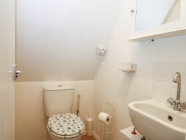 A small bathroom with a toilet a sink a mirror cabinet and a toilet paper holder at Chalet 58 - The Beach House in Kingsdown