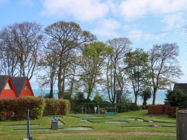 A mini golf course with small red cabins and trees by the sea at Chalet 58 - The Beach House in Kingsdown