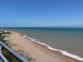 A beach with waves along the shore and some buildings in the distance at Chalet 58 - The Beach House in Kingsdown