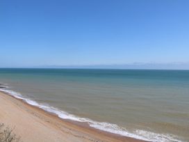 A beach with waves and ocean under a clear blue sky at Chalet 58 - The Beach House in Kingsdown