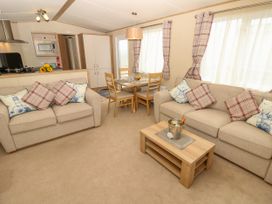 A living room with two beige sofas and a wooden coffee table next to a dining table with four chairs at Coastal Cottage in East Wittering
