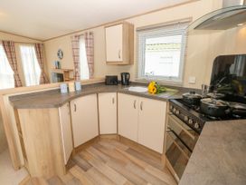 A kitchen with cabinets stove sink kettle and flowers on the counter at Coastal Cottage in East Wittering
