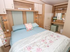 A bedroom with a bed blue bedding and floral blanket a pillow with text two bedside cabinets wardrobe and dressing table at Coastal Cottage in East Wittering