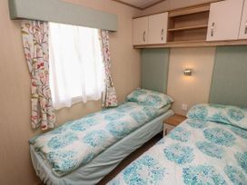 A bedroom with two single beds and overhead cabinets at Coastal Cottage in East Wittering