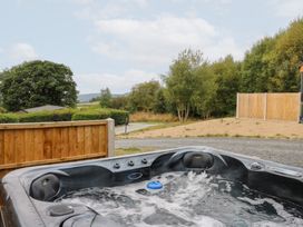 A hot tub with trees and a gravel path at Dam View Shepherds Hut in Upper Bwlch near Rhayader