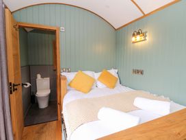 A bedroom with a bed and attached bathroom at Dam View Shepherds Hut Upper Bwlch near Rhayader