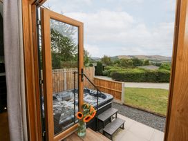 A view through a doorway showing a hot tub and flowers at Dam View Shepherds Hut Upper Bwlch near Rhayader