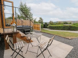 An outdoor patio with a table and chairs at Dam View Shepherds Hut Upper Bwlch near Rhayader