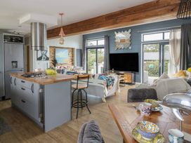 A kitchen and living area with bar stools and a television at Coogee View Maenygroes near New Quay