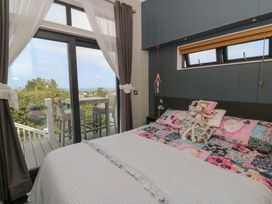 A bedroom with a bed and window leading to outdoor seating at Coogee View Maenygroes near New Quay