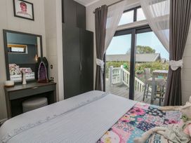 A bedroom with a bed and a window leading to a deck at Coogee View in Maenygroes near New Quay