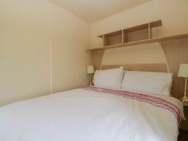A bedroom with a double bed white bedding and two lamps on bedside tables at Hollie in Raglan