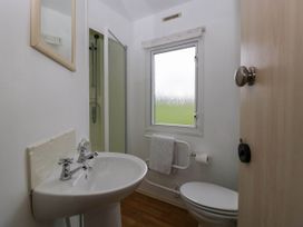 A bathroom with a sink a mirror a shower a toilet and a window with a towel on a rail at Hollie in Raglan