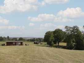 Cabins in a grass field with trees at Hollie in Raglan