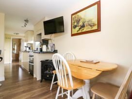 A kitchen with a wooden dining table and chairs a mounted television and a painting of tigers on the wall at Poppy in Raglan