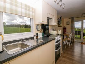 A kitchen with a sink stove toaster dining table and chairs overlooking a grassy field at Poppy in Raglan