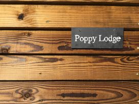 A wooden wall with a black sign displaying Poppy Lodge at Poppy in Raglan