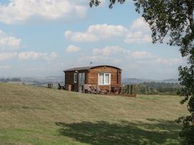 A wooden cabin with a deck and chairs at Poppy in Raglan