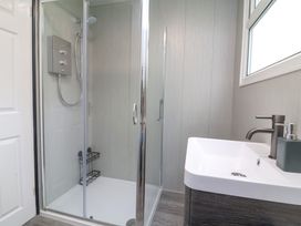 A bathroom with a glass shower enclosure and a sink under a window at Number 24 The Park in Kilkhampton