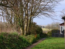 A pathway next to trees and shrubs with a house and deck on the right at Number 24 The Park Kilkhampton