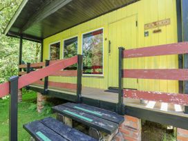 Front porch with steps and railing leading to a yellow door of a lodge at Lodge 2 - Rowan in Glenkiln near Lamlash