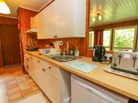 A kitchen with white cabinets wooden countertops a sink toaster kettle and window at Lodge 2 - Rowan in Glenkiln near Lamlash