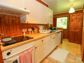 A kitchen with white cabinets a stove a sink a toaster and a window at Lodge 2 - Rowan in Glenkiln near Lamlash