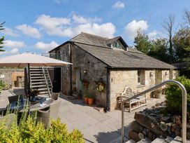 An outdoor area with a stone building, stairs, and seating at Stable Loft in Watergate Bay
