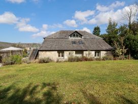 An exterior view of a stone house with a sloped roof and garden at Stable Loft in Watergate Bay