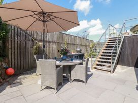 An outdoor patio with a table and chairs under an umbrella at Stable Loft in Watergate Bay