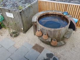 A garden with a hot tub and wooden deck at Stable Loft in Watergate Bay