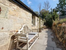 An outdoor space with a bench and stone wall at Stable Loft Watergate Bay