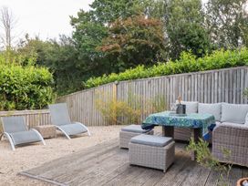An outdoor seating area with lounge chairs and a table at Stable Loft in Watergate Bay