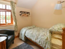 A bedroom with a single bed with butterfly patterned bedding a chair a window and a wall-mounted clothes rack at Ty Pili Pala in Betws-Y-Coed