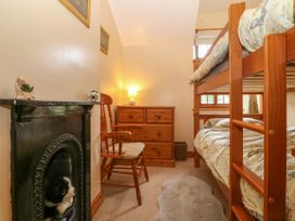 A bedroom with bunk beds a wooden chair a dresser a lamp and a fireplace at Ty Pili Pala in Betws-Y-Coed