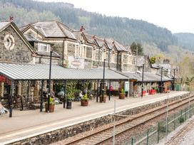 A train station platform with benches pots and a clock at Betws-Y-Coed