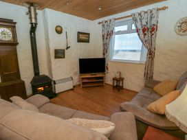 A living room with a clock, stove, and television at Harbour High Annex in Fishguard