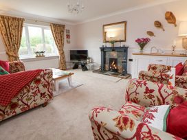 A living room with patterned armchairs a fireplace and a television at 2 Mountain View in Chirk